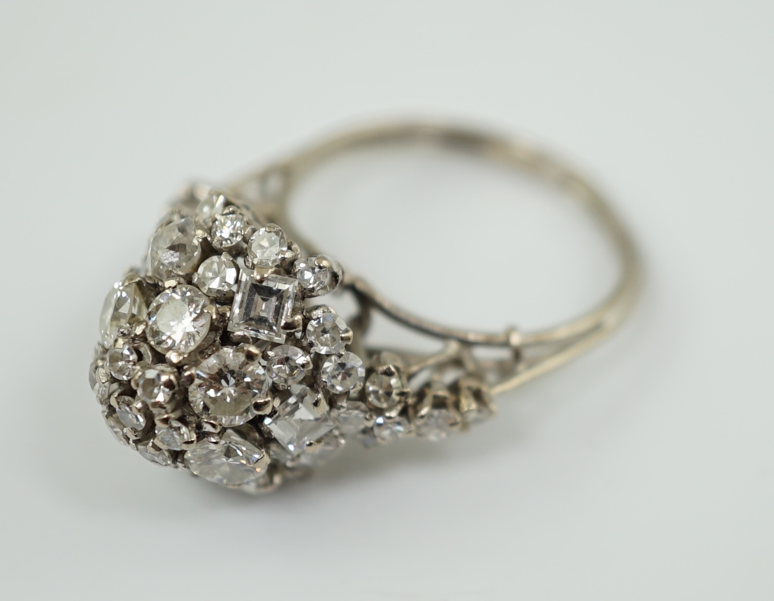 A mid 20th century platinum? and diamond cluster set dome shaped dress ring, with diamond set shoulders